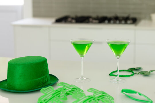 Two martini glasses are sitting on glossy white countertop in modern kitchen, with green shamrocks