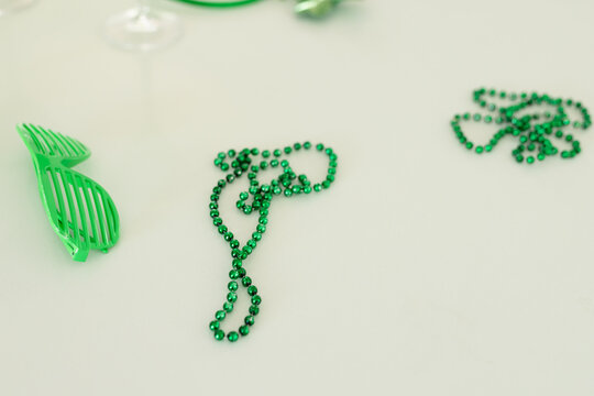 Green metallic bead necklace is lying slightly tangled on tabletop, with shutter glasses blurred