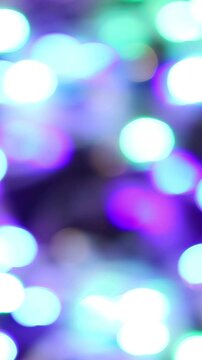 Una toma de cerca de varias luces de colores en forma de c&iacute;rculos en movimiento en la oscuridad. Desenfoque. Video vertical