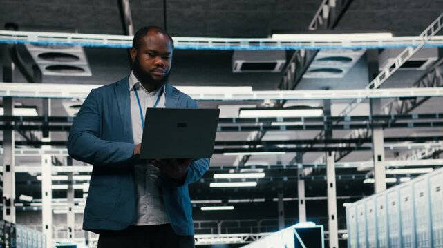 Optimizing electronics, laptop and team of software developers in server farm. Brainstorming, notebook and teamworking colleagues in data center monitoring system performance bottlenecks, camera B