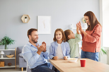 Parents and kids enjoy leisure time at home, playing a game together. The family celebrates victory...