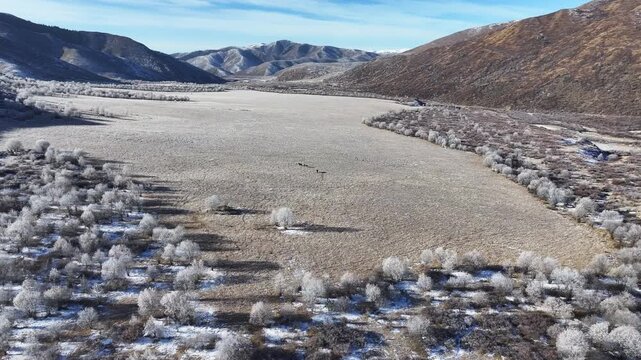 Aerial view of snowy alpine pastures and mountain ranges in Aba, Sichuan, featuring grazing horses and rime on the winter plateau