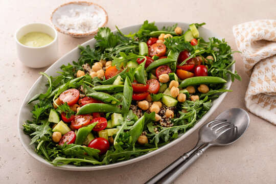 Fresh vegetables and quinoa salad with chickpeas, arugula and fresh peas with avocado ranch dressing
