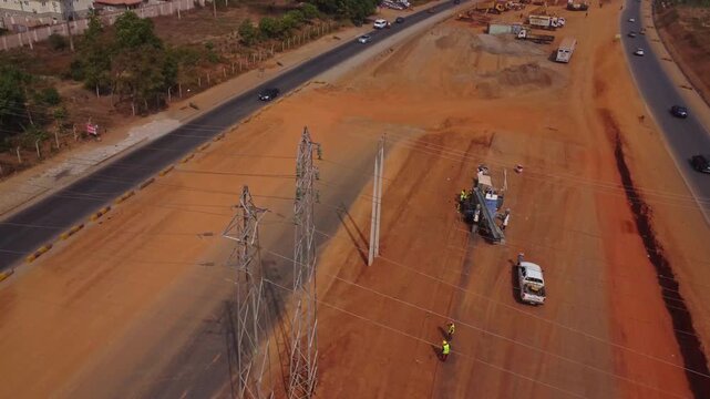 Jib up of workers using brooms to clear sand at the construction site of a large road along APO in Abuja, Nigeria