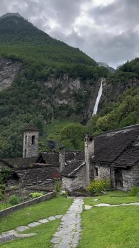 Foroglio Waterfall cascade cliffs behind traditional stone houses Rustici Switzerland vertical video