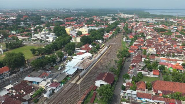 Drone view flying over the city of probolinggo, east java. An aerial perspective of the railway station, urban landscape, and the java sea