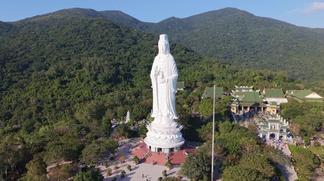 Giant White Statue Overlooking Forested Hills And Lotus Pedestal, Aerial View Of Temple Complex At Son Tra, Da Nang, Vietnam With Visitors On Courtyard, Morning Light, Peaceful Pilgrimage