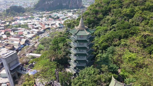 Aerial Temple Sanctuary Near Da Nang, Lush Vegetation Surrounds Towering Pagoda With Limestone Hill Backdrop, Mossy Green Tiles And Secluded Shrine Pathways, Slow Cinematic Drone Reveal,