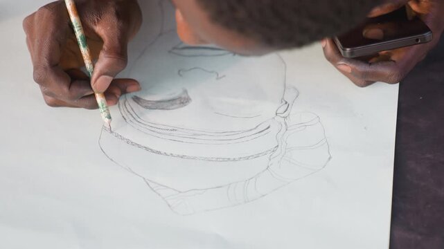 Detailed pencil outline black portrait drawing. Meticulous view of black male artist mapping facial features with careful pencil strokes and mobile reference, dotted stipple marks shaping tonal