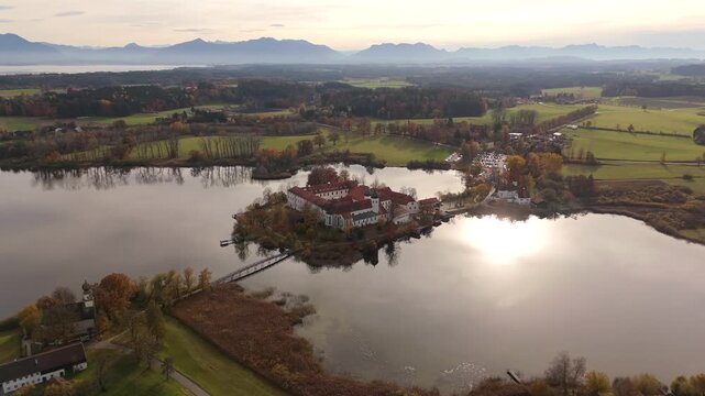 Luftaufnahme Kloster Seeon in Seeon-Seebruck, Oberbayern, Deutschland. Drohnenflug uber Kloster Seeon und Abtskapelle St. Nikolaus. Cinematic video captures architecture, lake and alpine background