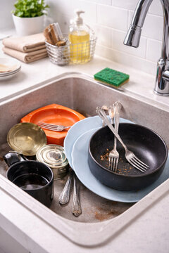 Dirty dishes in the kitchen sink after cooking&mdash;plates, bowls, cups, and cutlery before washing. 