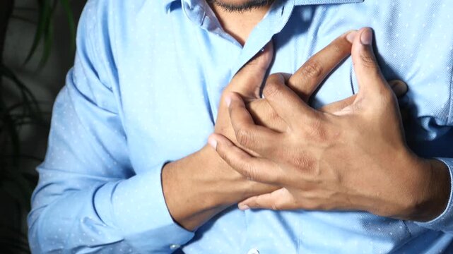 Young man experiencing sudden sharp chest pain while holding his heart in distress