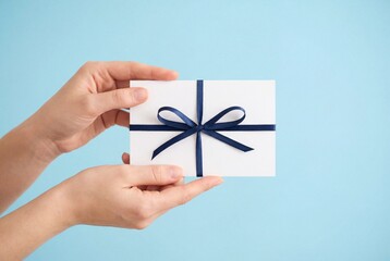 Obraz premium Woman hands holding white gift card with blue ribbon