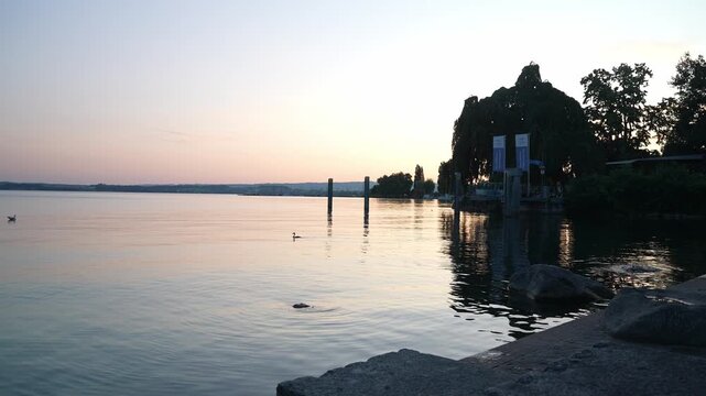 Tranquil sunset over Lake Zug in Switzerland with calm water, soft reflections, lakeside trees and evening sky creating peaceful scenic atmosphere