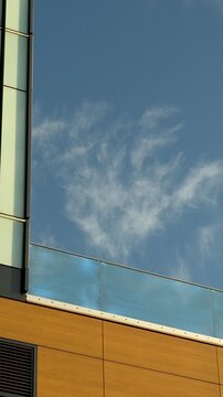 A vertical shot showcasing the modern architectural design of a business building in , featuring wood panels, glass balconies, and a clear blue sky.