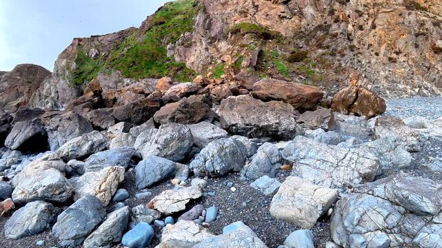 panning upwards coastal rockfall after winter storm and high tides Waterford coast ireland