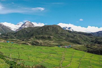 Obraz premium Beautiful mountainous landscape with green fields and snow-capped peaks
