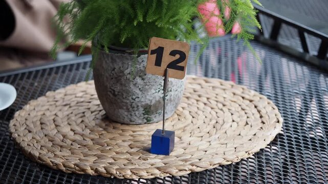 Table with number 12 and plant on a metal surface