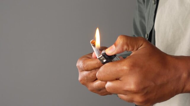 Lighting a cigarette with a lighter in hands
