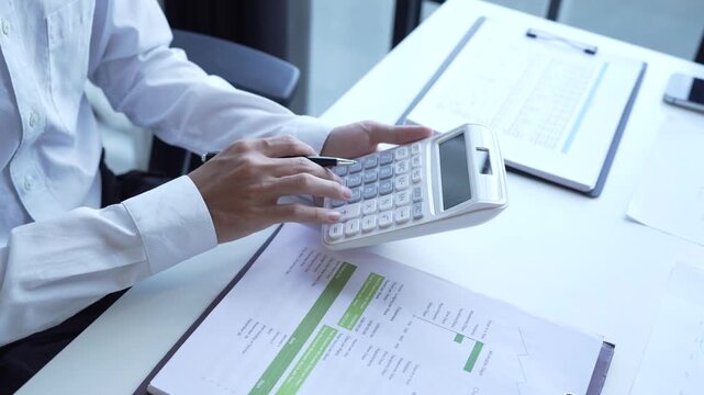 Businessman holding and press botton on calculator over documents