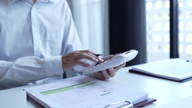 Businessman holding and press botton on calculator over documents