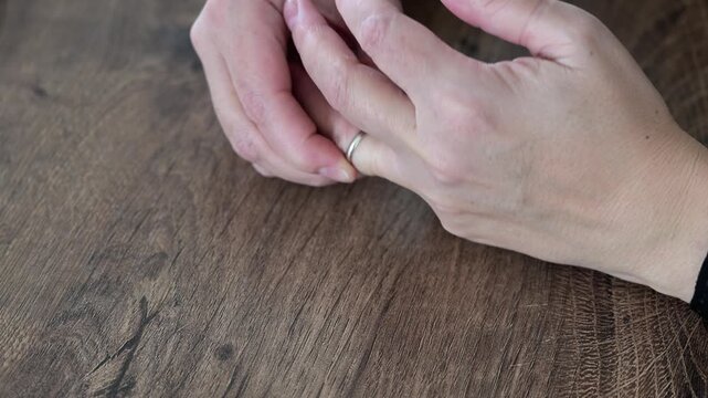 Close up of womans hands removing wedding ring. Symbolic moment representing divorce and emotional transition.