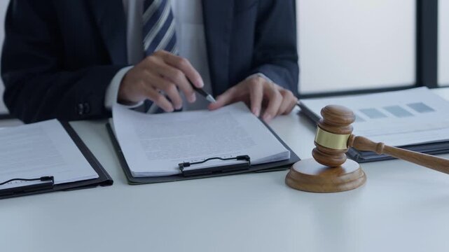 Lawyer holding pen checking documents with gavels on desk