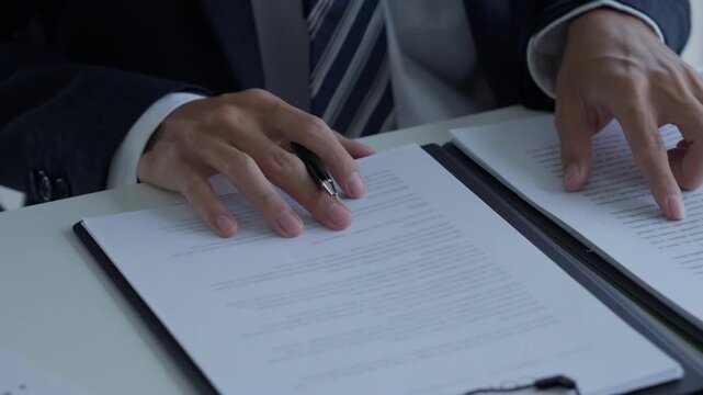 Lawyer holding pen checking documents with gavels on desk