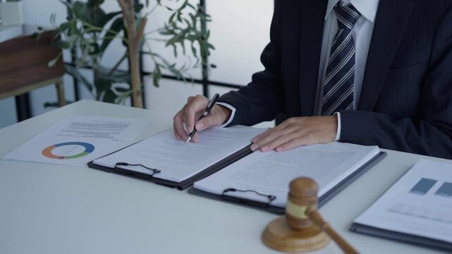 Lawyer holding pen checking documents with gavels on desk