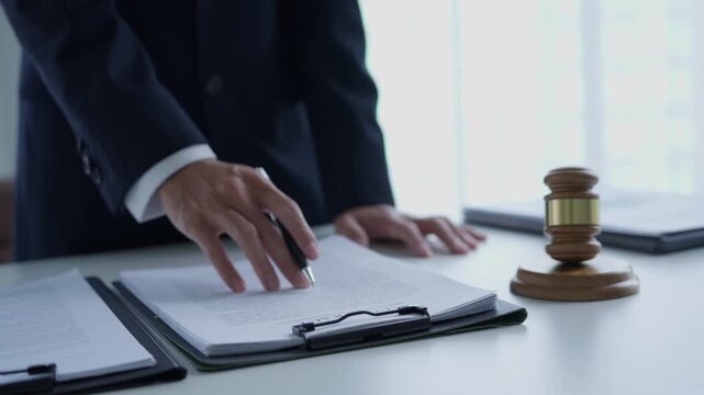 Lawyer holding pen checking documents with gavels on desk