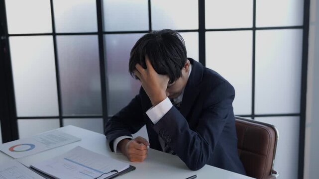 Stressed businessman holding head hard working in office