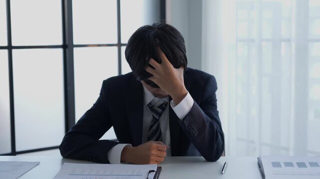 Stressed businessman holding head hard working in office
