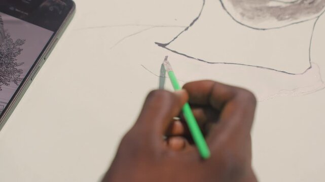 Artist sketches carefully. Closeup of artist refining sketch into painted shape with focus. Artist meticulously tracing and enhancing outline on paper using green brush with steady hand