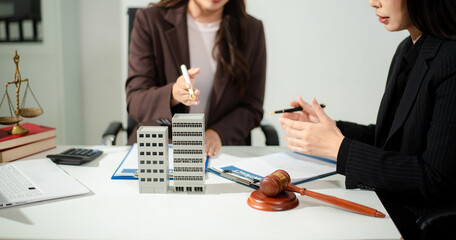 Real estate lawyer reviewing property contract with building model and gavel, concept of investment agreement, mortgage consultation, legal compliance © laddawan