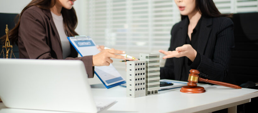 Real estate lawyer reviewing property contract with building model and gavel, concept of investment agreement, mortgage consultation, legal compliance