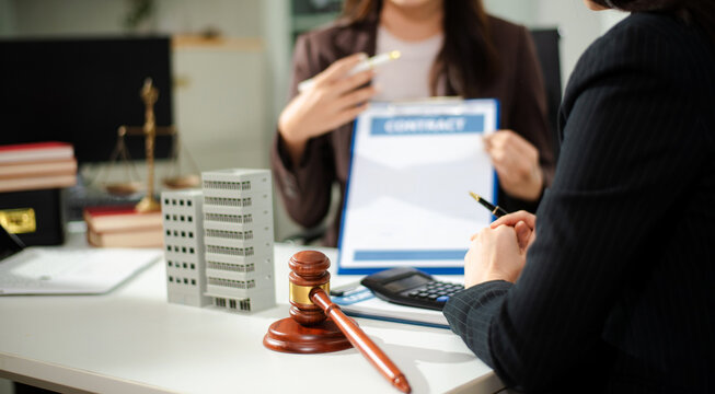 Real estate lawyer reviewing property contract with building model and gavel, concept of investment agreement, mortgage consultation, legal compliance