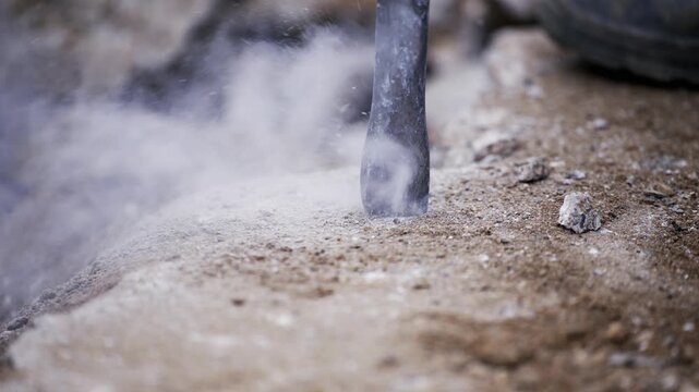 Road worker drilling asphalt on pavement with jackhammer, slow motion