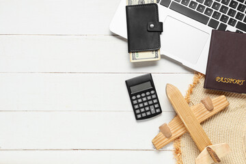 Laptop with money, passport, calculator and airplane on white wooden background. Travel budget concept