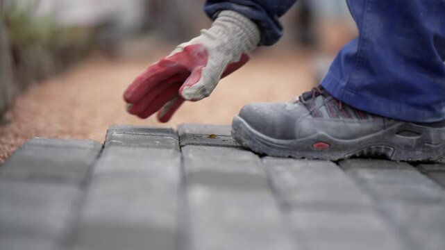 Laying gray concrete paving slabs in house courtyard on sand foundation base, slow motion