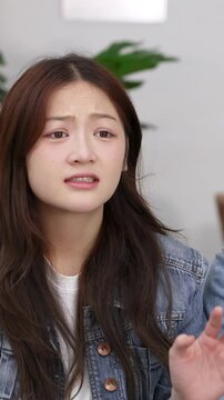 Young Asian Woman Expressing Disgust and Worry in a Living Room