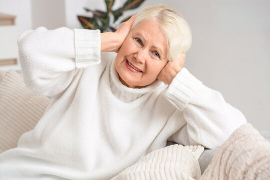 Senior woman on sofa suffering from loud neighbours at home