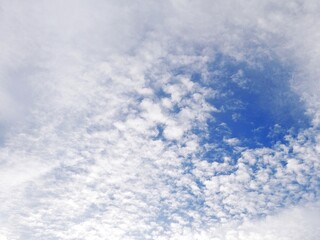 Beautiful white clouds floating in a clear blue sky. Natural daylight sky background with soft clouds. Blue sky texture with a calm and clean pattern.