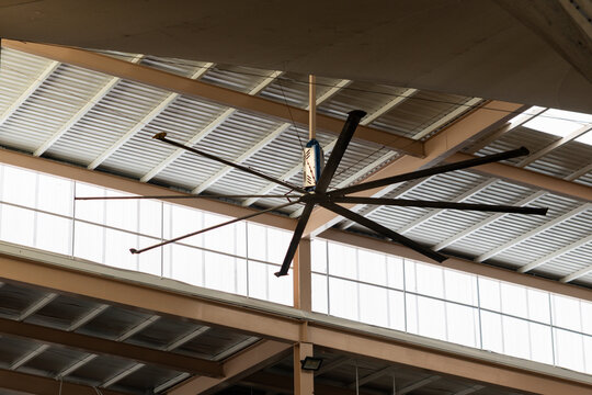 Industrial ceiling fan spins beneath metal roof panels