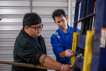 Mechanics collaborating on forklift repair and maintenance in workshop © Apichat