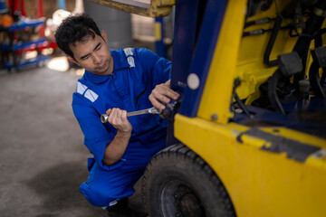 Mechanic repairing forklift using wrench in workshop © Apichat