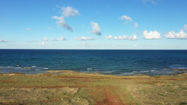 Wide view of the rocky Adriatic coastline with gentle waves and a clear blue sky near Brindisi, Italy. Natural seascape ideal for travel and nature concepts.