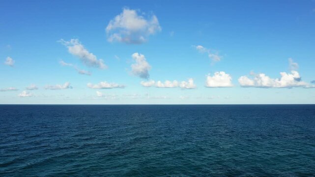 Wide view of the tranquil blue sea under a clear sky with scattered clouds, captured near Brindisi, Italy. Perfect for concepts of serenity, travel, and nature.
