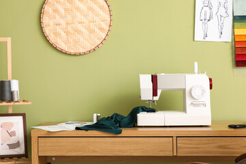 Tailor's workplace with sewing machine near green wall in atelier © Pixel-Shot