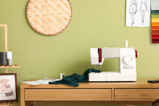 Tailor's workplace with sewing machine near green wall in atelier