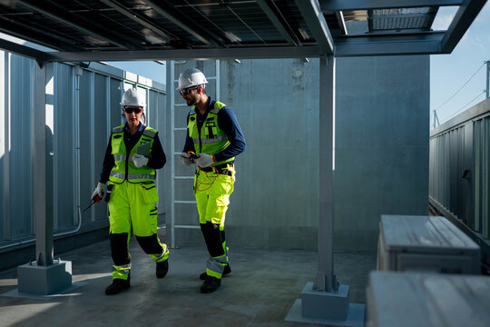 Male and female engineers inspecting photovoltaic systems beneath solar panel
